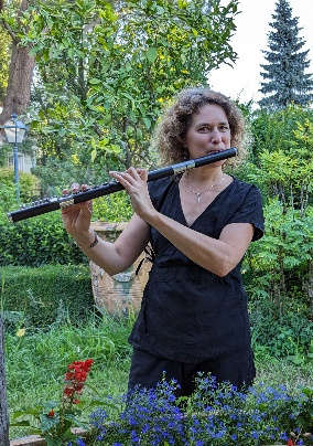 Elisabeth Madaule jouant de la flûte traversière dans un jardin verdoyant